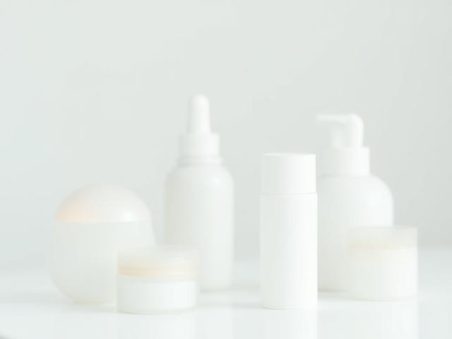 Susunan botol produk penjagaan kulit gred profesional yang elegan dan bersih di atas meja kaca.